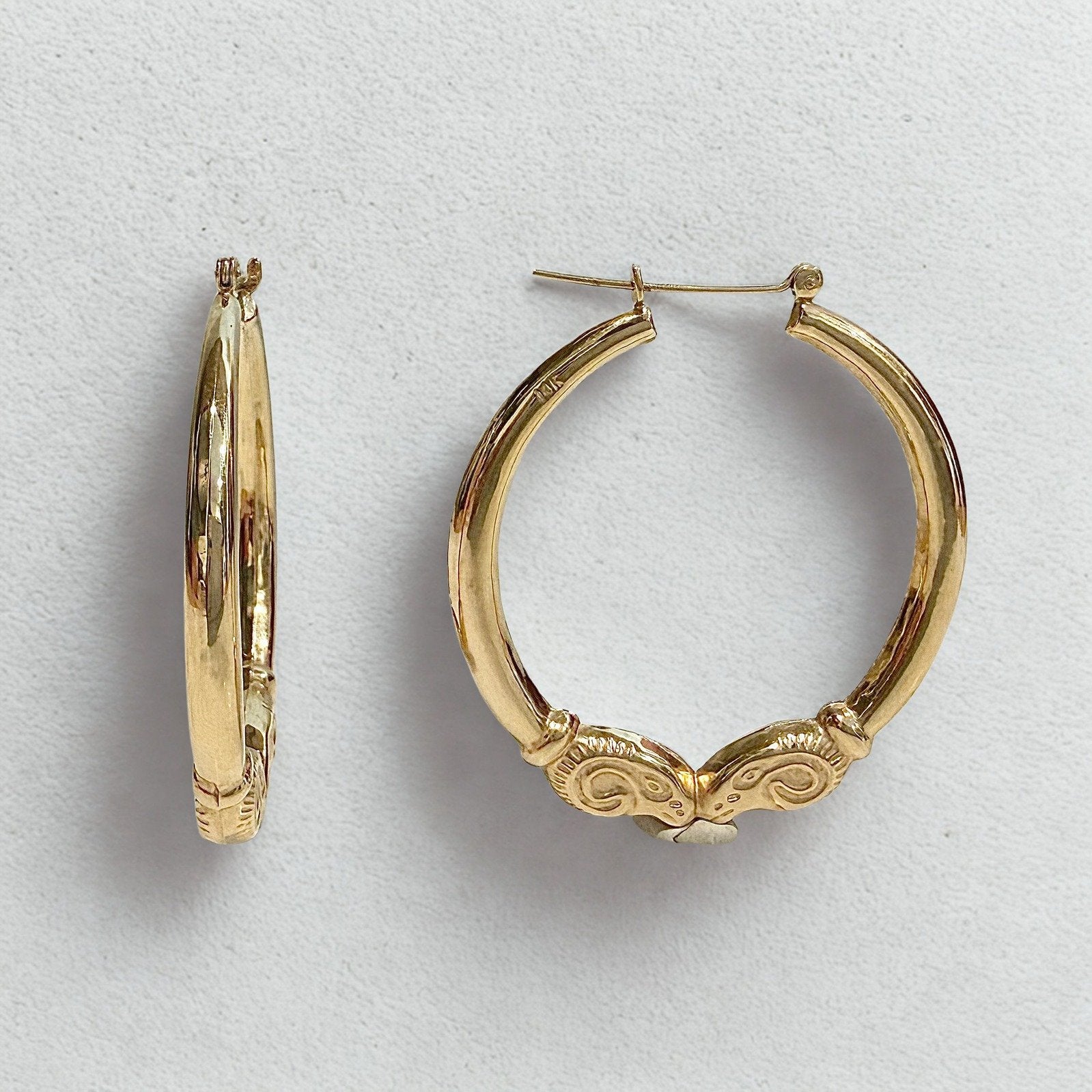 Pre-owned | 14k yellow gold ram head hoop earrings featuring a polished design and hinged posts.