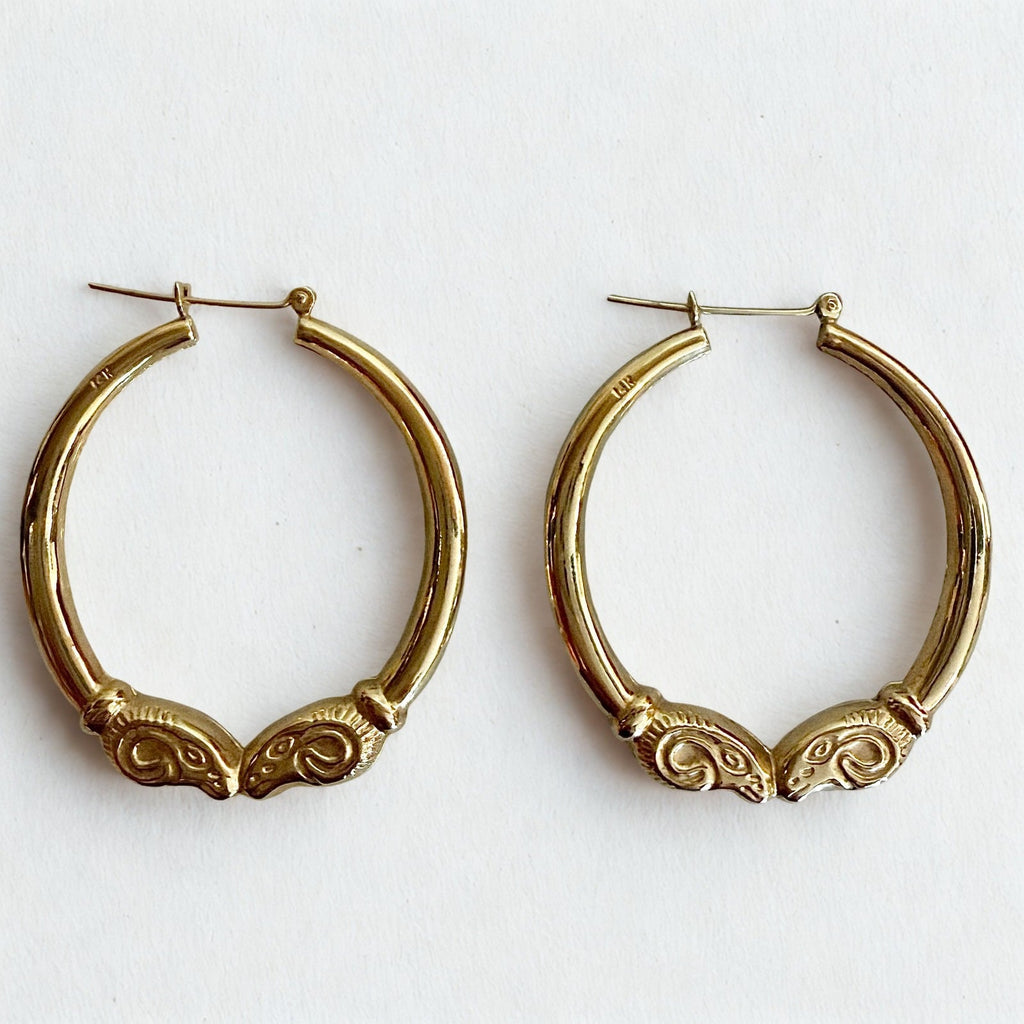 Pre-owned | 14k yellow gold ram head hoop earrings featuring a polished design and hinged posts.