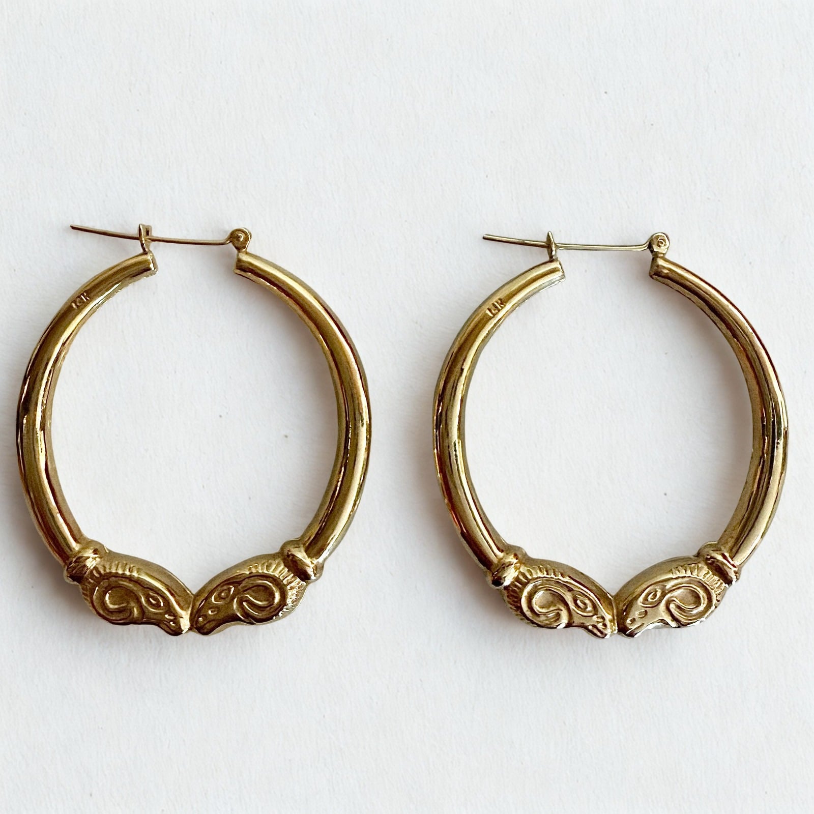 Pre-owned | 14k yellow gold ram head hoop earrings featuring a polished design and hinged posts.